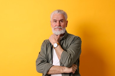 Photo of Portrait of senior man with gray beard on orange background