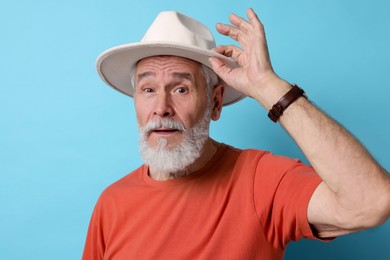 Photo of Stylish senior man in hat on light blue background