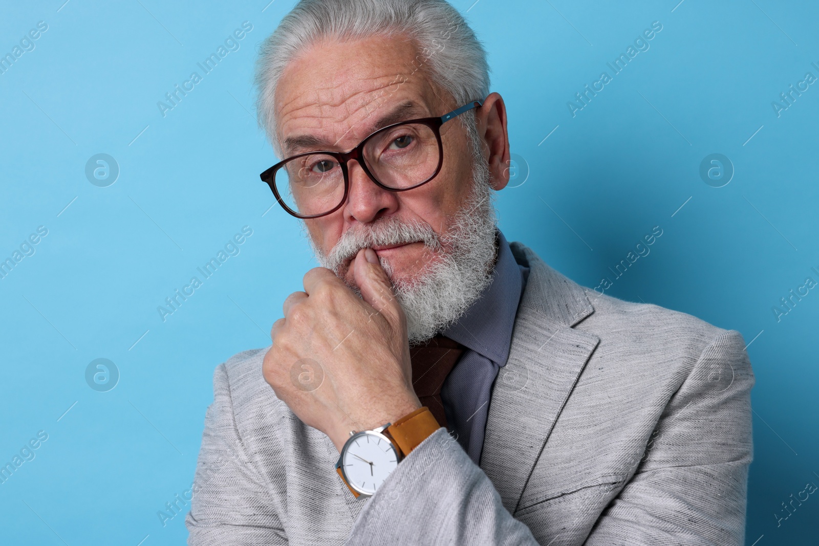 Photo of Portrait of serious senior man with silver beard on light blue background