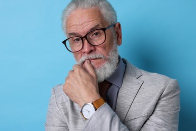 Photo of Portrait of serious senior man with silver beard on light blue background