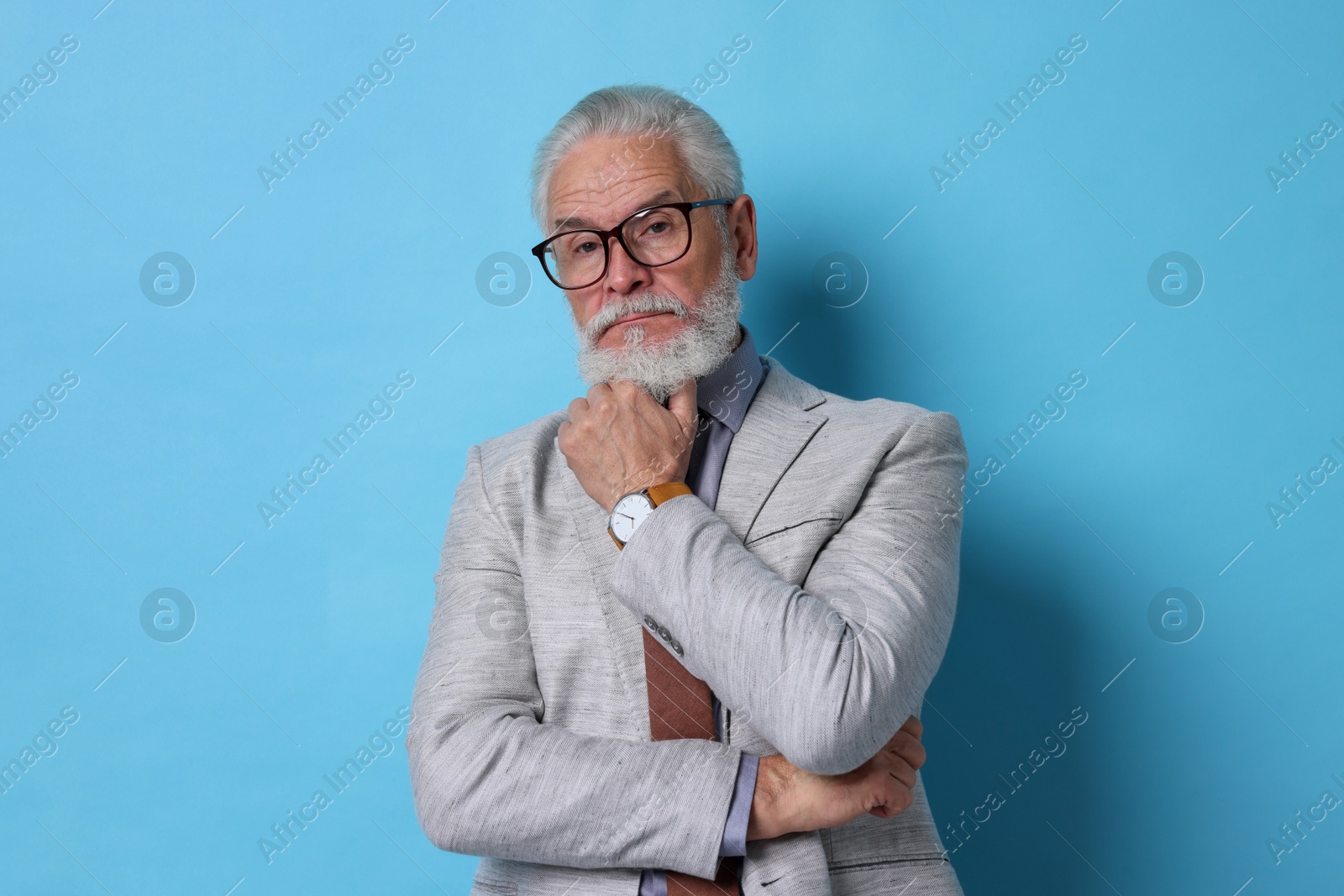 Photo of Portrait of serious senior man with silver beard on light blue background