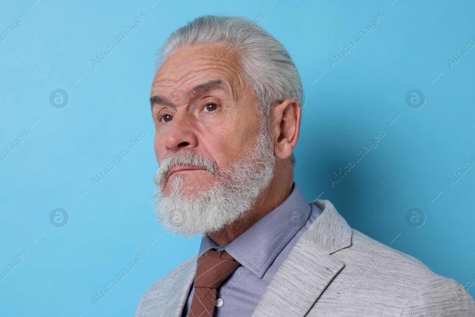 Photo of Portrait of serious senior man with silver beard on light blue background