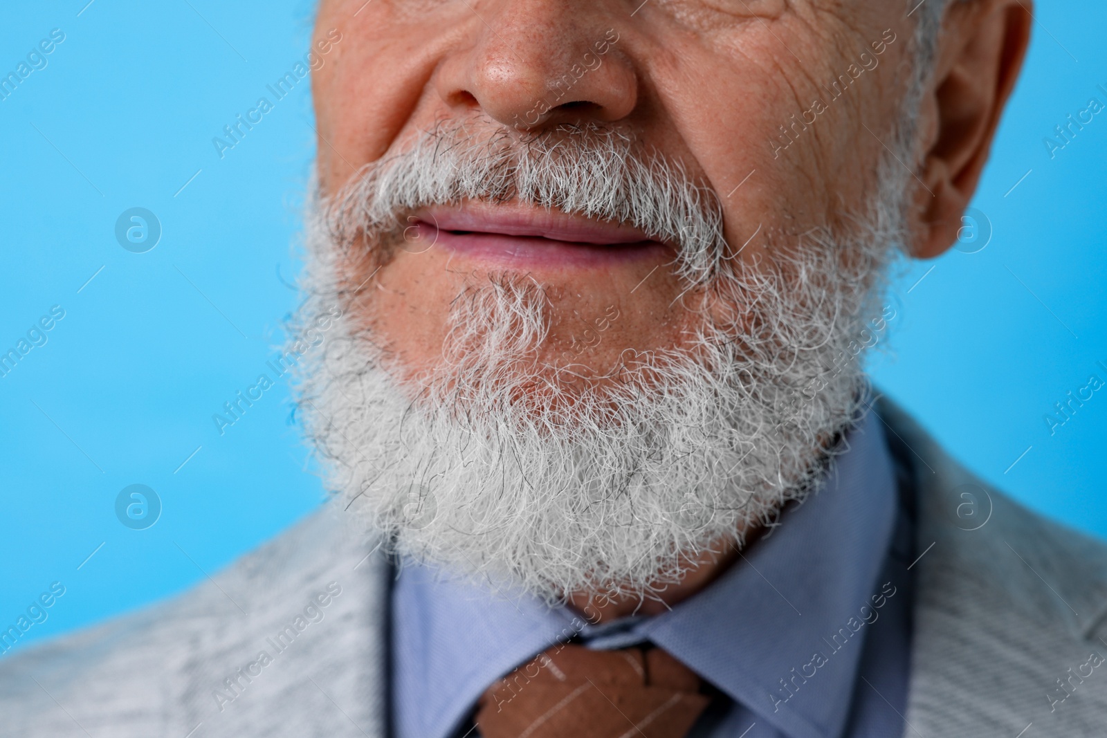 Photo of Senior man with gray beard on light blue background, closeup