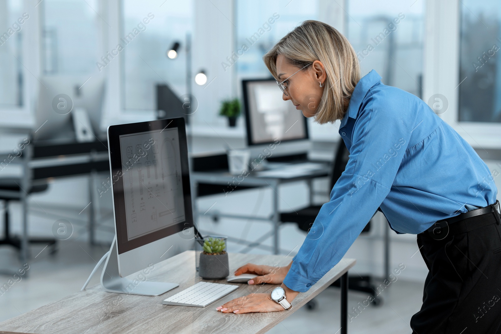 Photo of Technician making digital engineering drawing on computer at desk in office