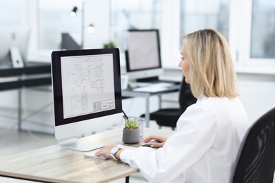 Photo of Technician making digital engineering drawing on computer at desk in office