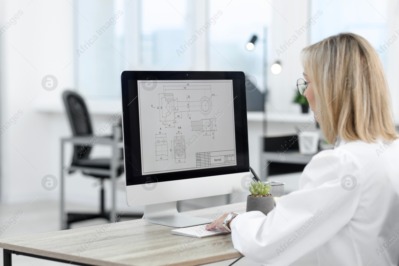 Photo of Technician making digital engineering drawing on computer at desk in office