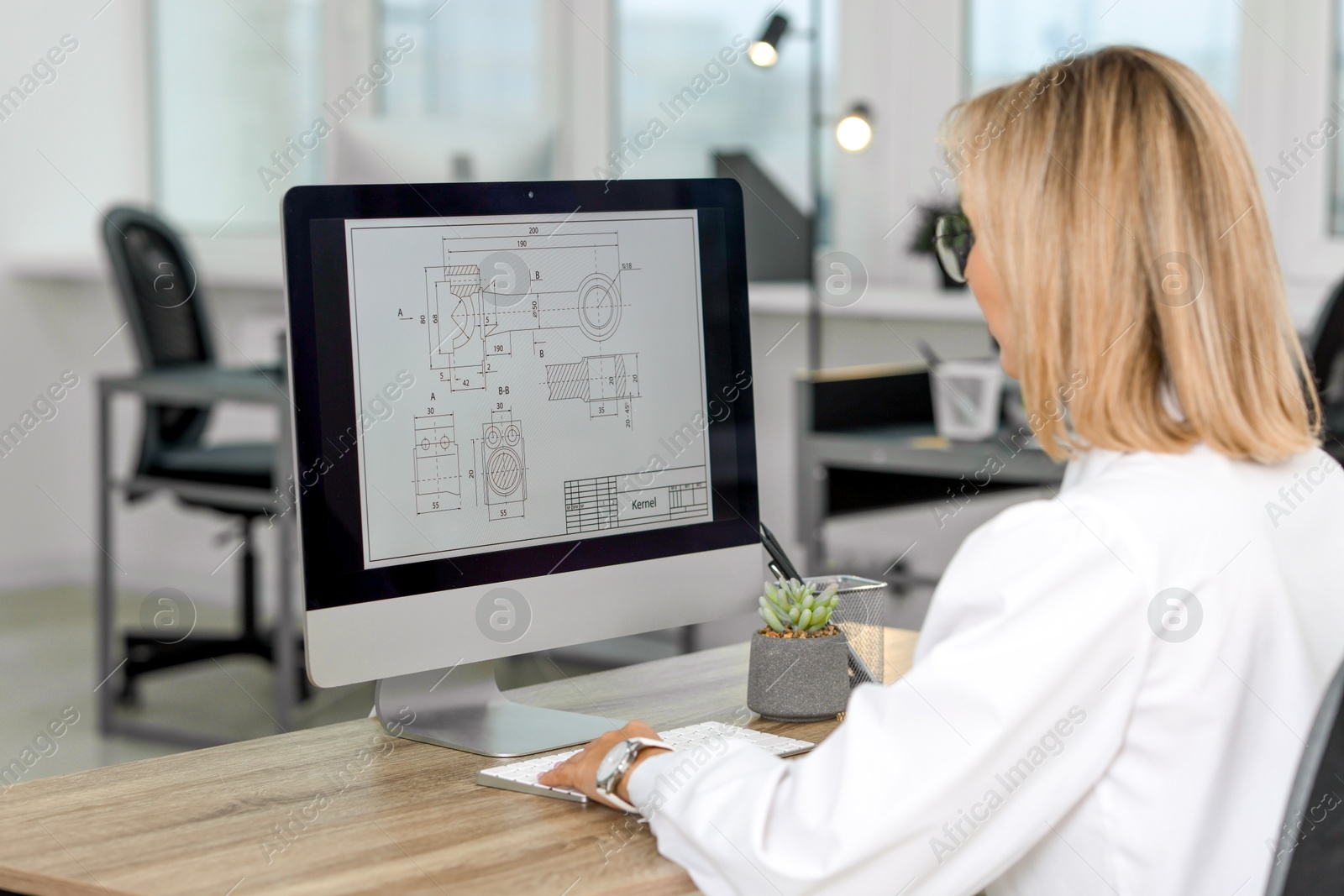 Photo of Technician making digital engineering drawing on computer at desk in office