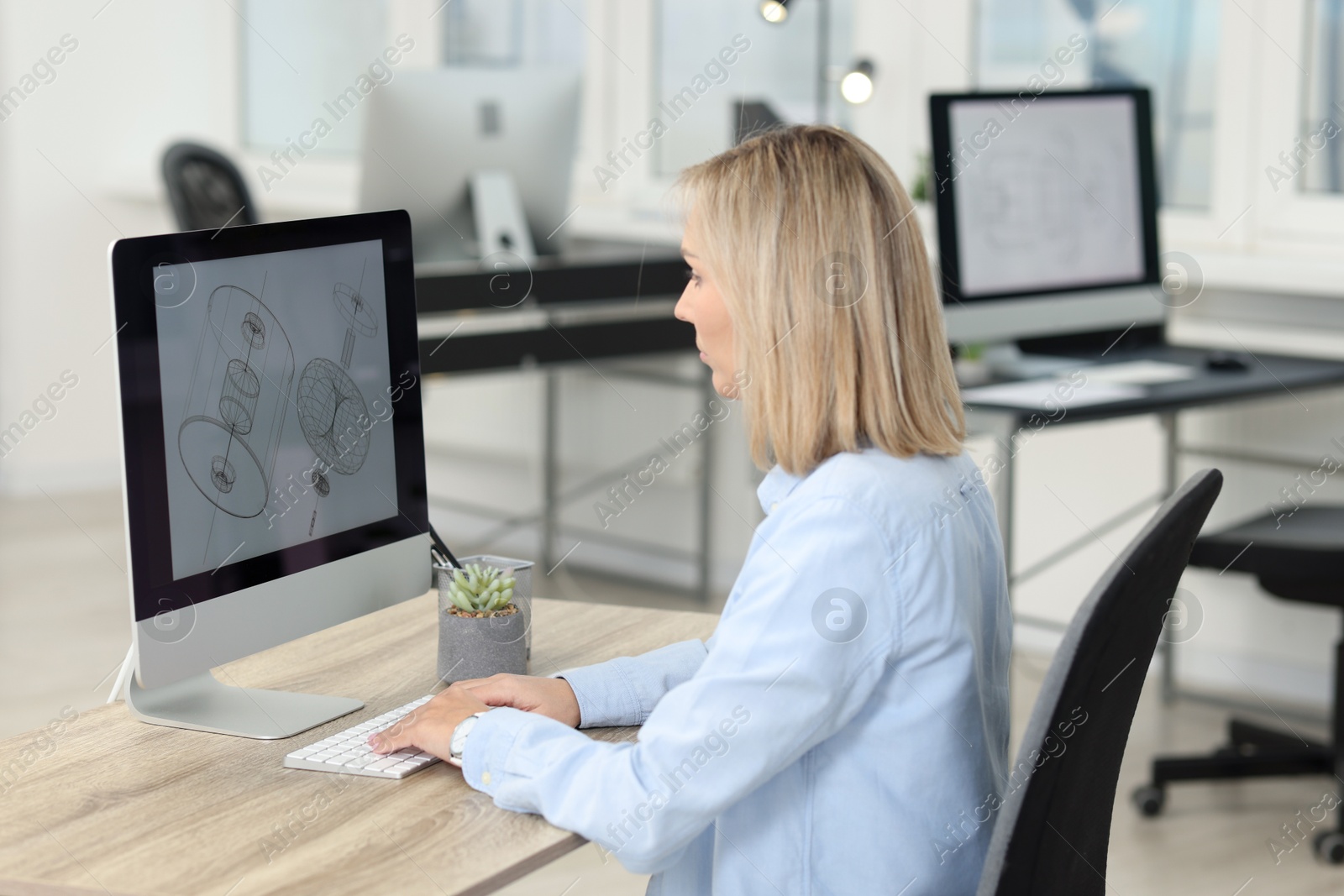 Photo of Technician making digital engineering drawing on computer at desk in office