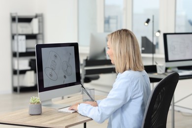 Photo of Technician making digital engineering drawing on computer at desk in office