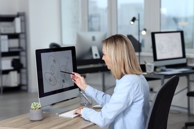 Photo of Technician making digital engineering drawing on computer at desk in office