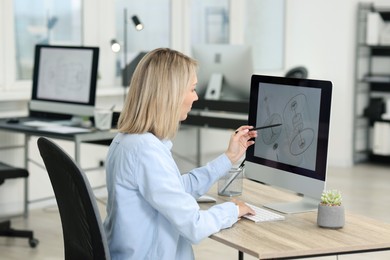 Photo of Technician making digital engineering drawing on computer at desk in office