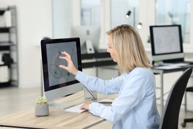 Photo of Technician making digital engineering drawing on computer at desk in office