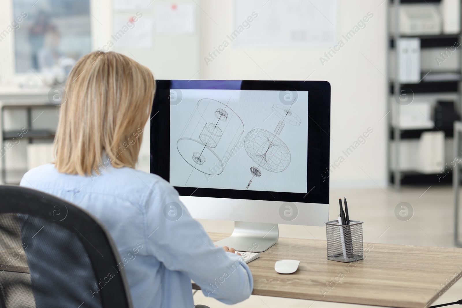 Photo of Technician making digital engineering drawing on computer at desk in office, back view