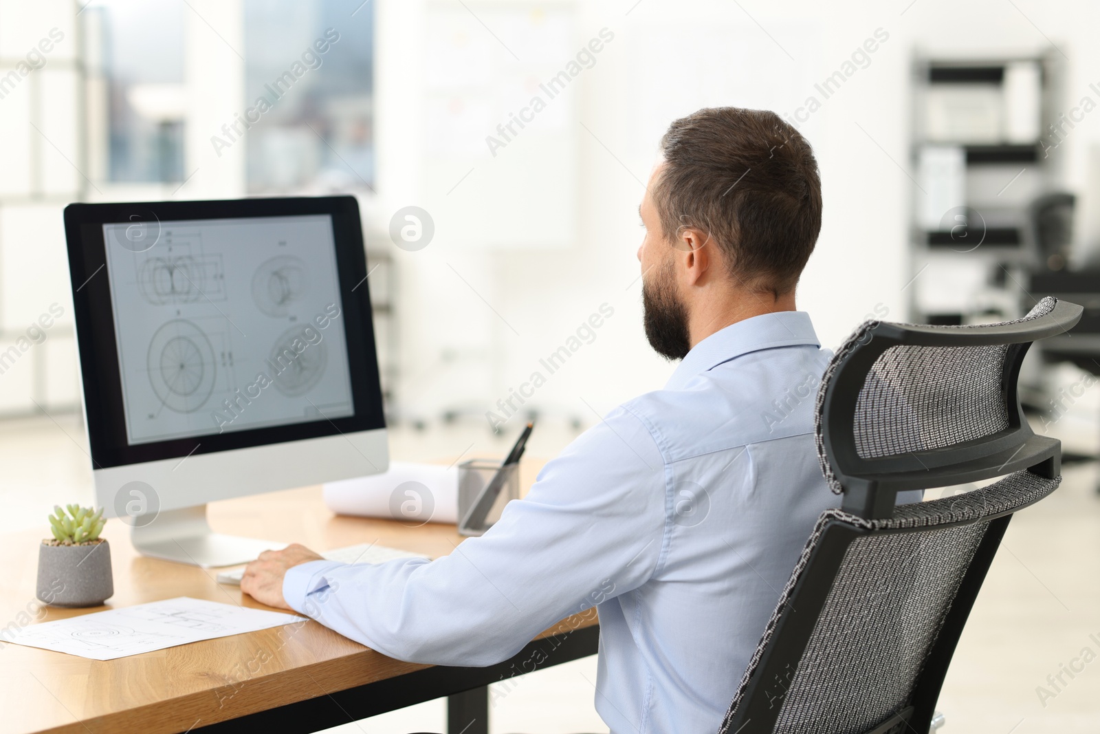 Photo of Technician making digital engineering drawing on computer at desk in office