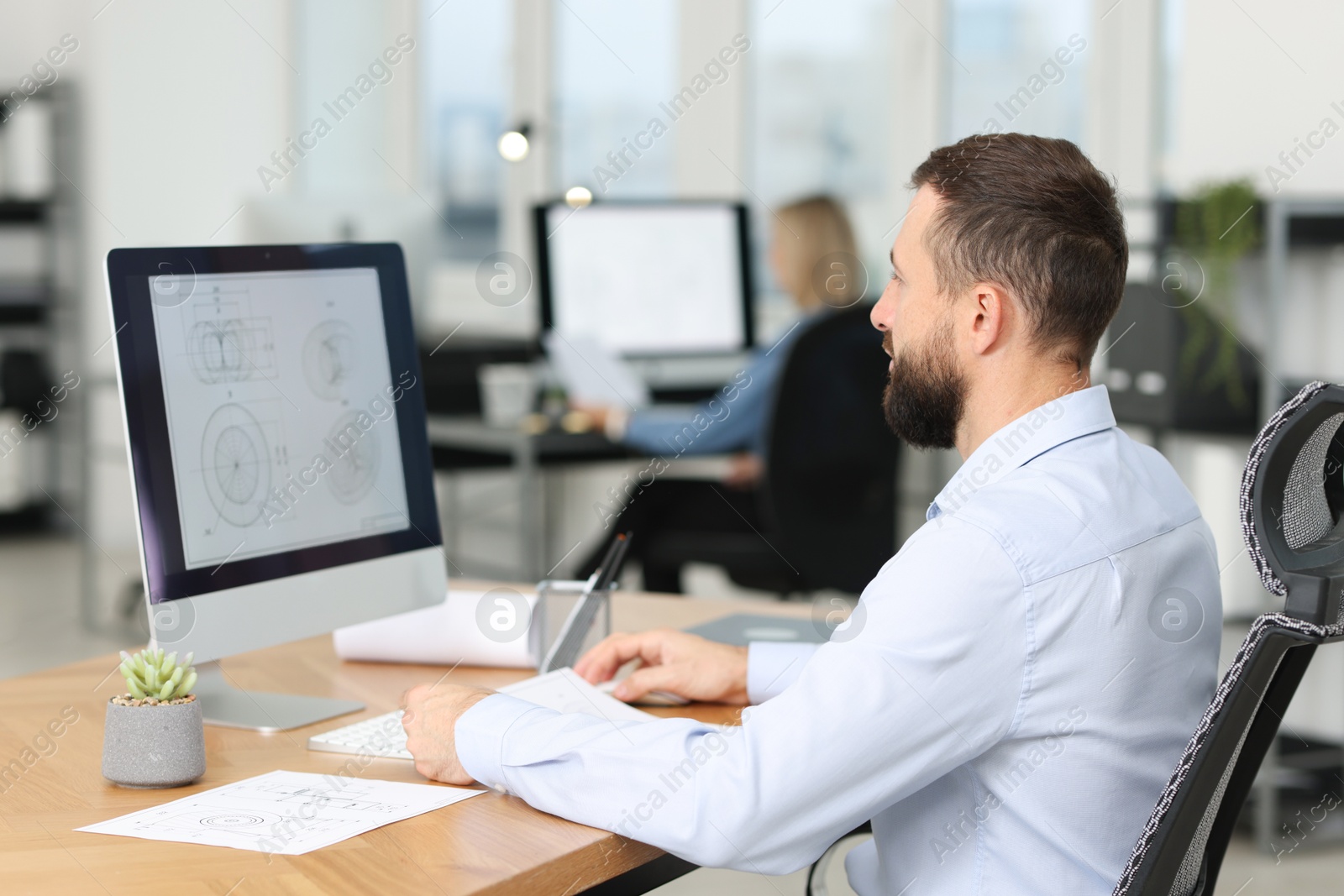 Photo of Technician making digital engineering drawing on computer at desk in office