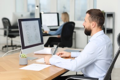 Photo of Technician making digital engineering drawing on computer at desk in office