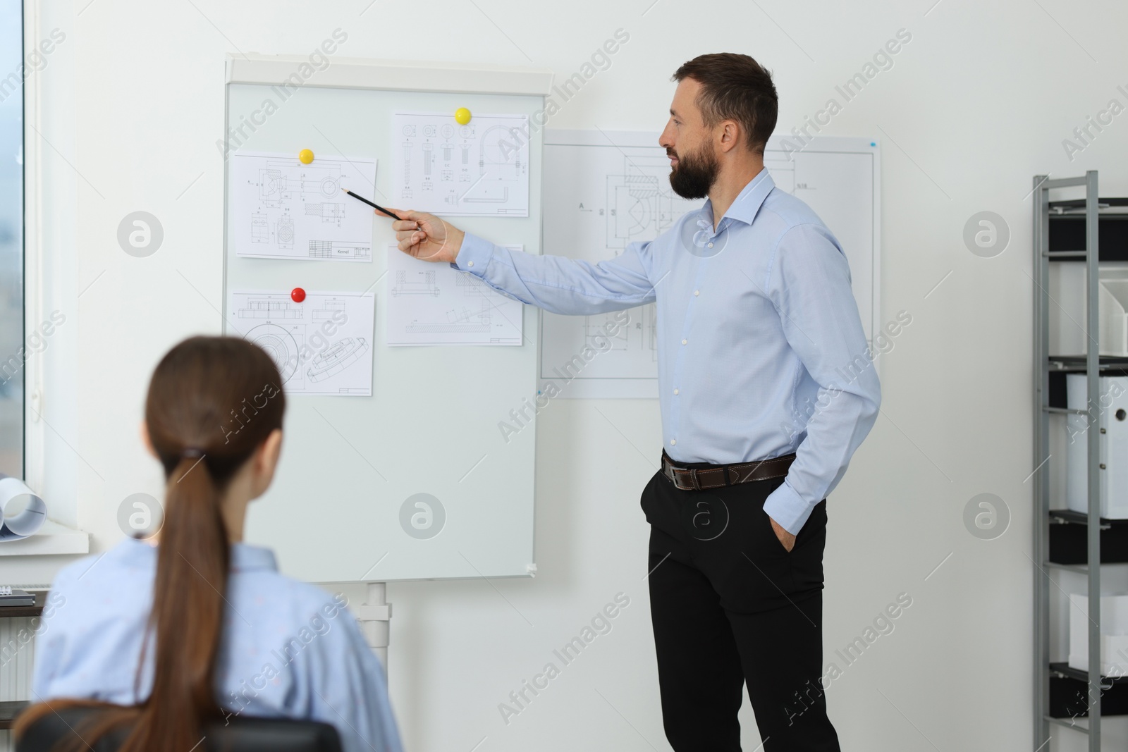 Photo of Man making presentation with engineering drawings to his colleagues in office