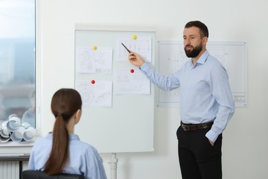 Photo of Man making presentation with engineering drawings to his colleagues in office