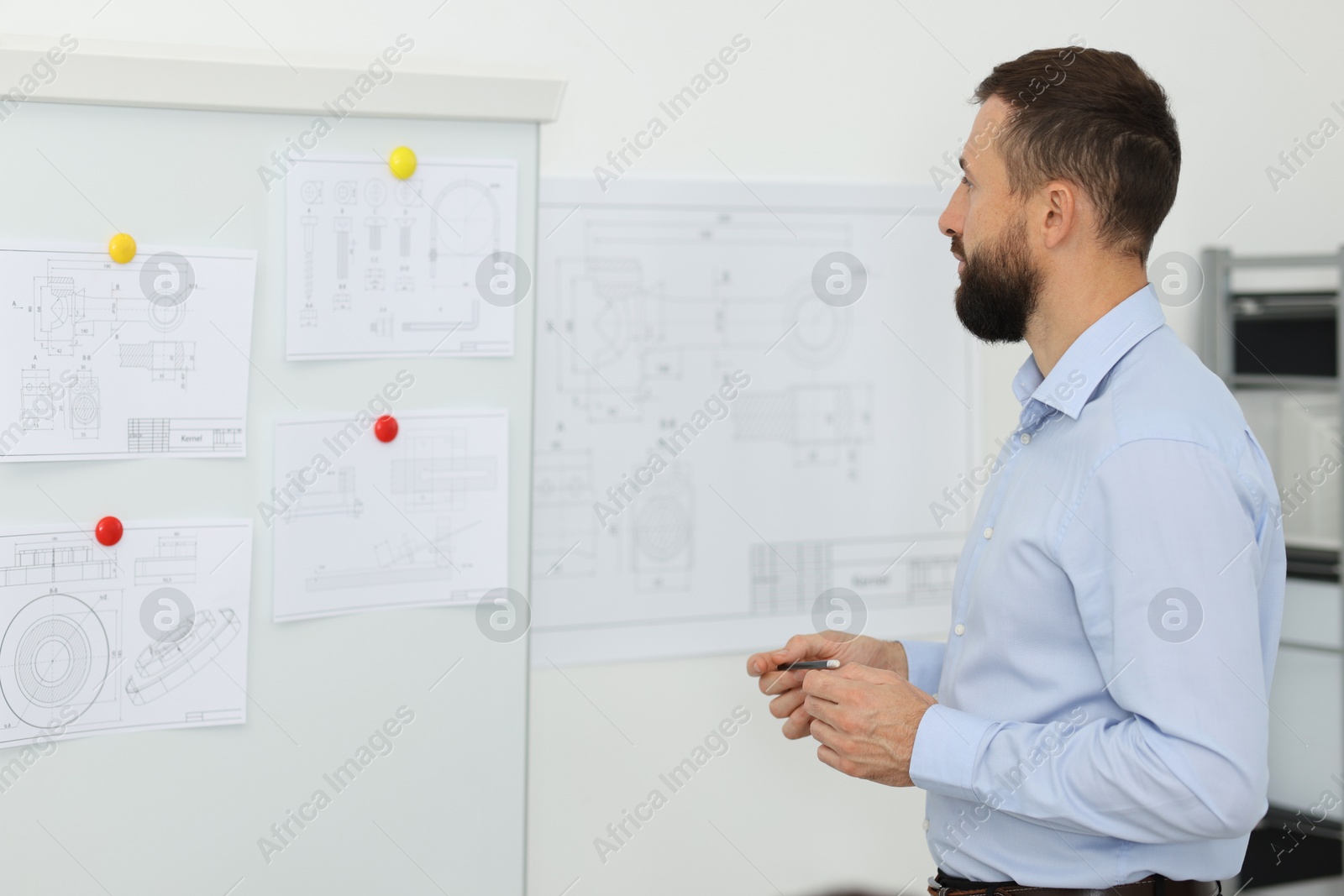 Photo of Man making presentation with engineering drawings to his colleagues in office