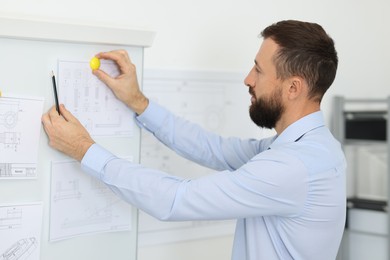 Photo of Man making presentation with engineering drawings to his colleagues in office