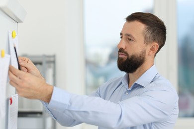 Photo of Man making presentation with engineering drawings to his colleagues in office