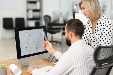 Photo of Technicians making digital engineering drawing on computer at desk in office