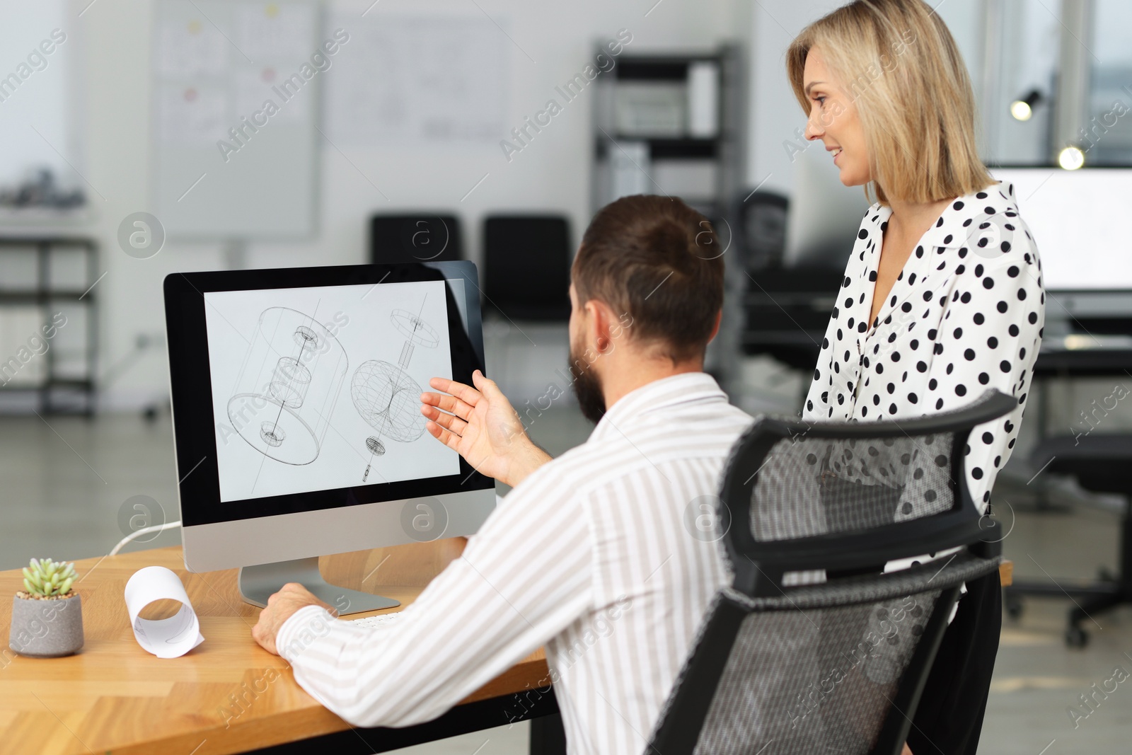 Photo of Technicians making digital engineering drawing on computer at desk in office