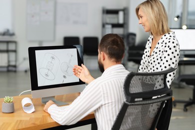 Photo of Technicians making digital engineering drawing on computer at desk in office