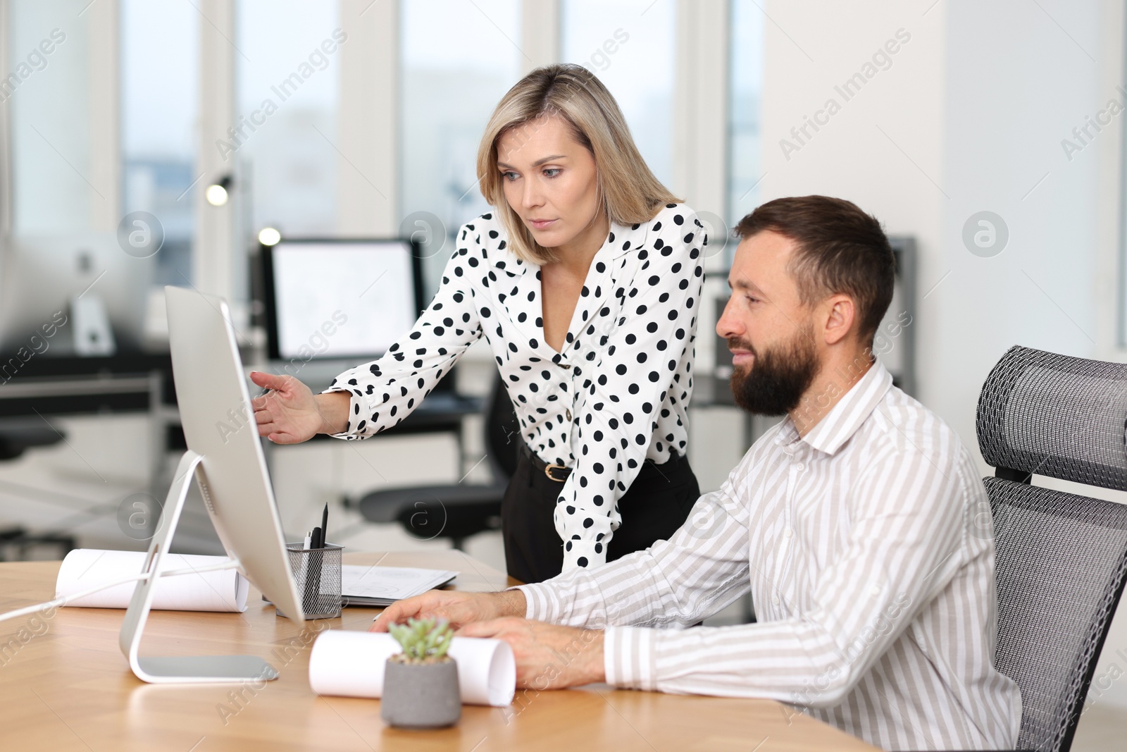 Photo of Technicians making digital engineering drawing on computer at desk in office