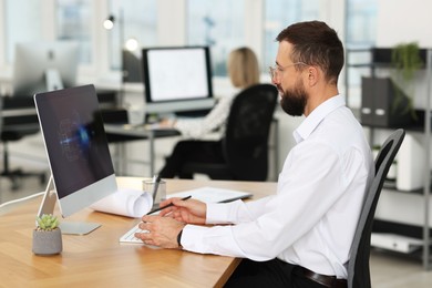 Photo of Technician making digital engineering drawing on computer at desk in office