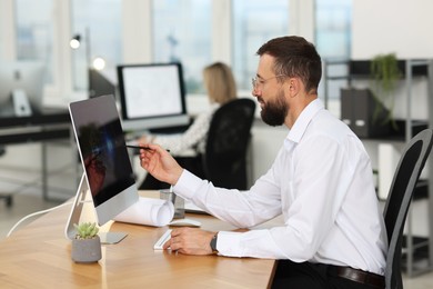 Photo of Technician making digital engineering drawing on computer at desk in office