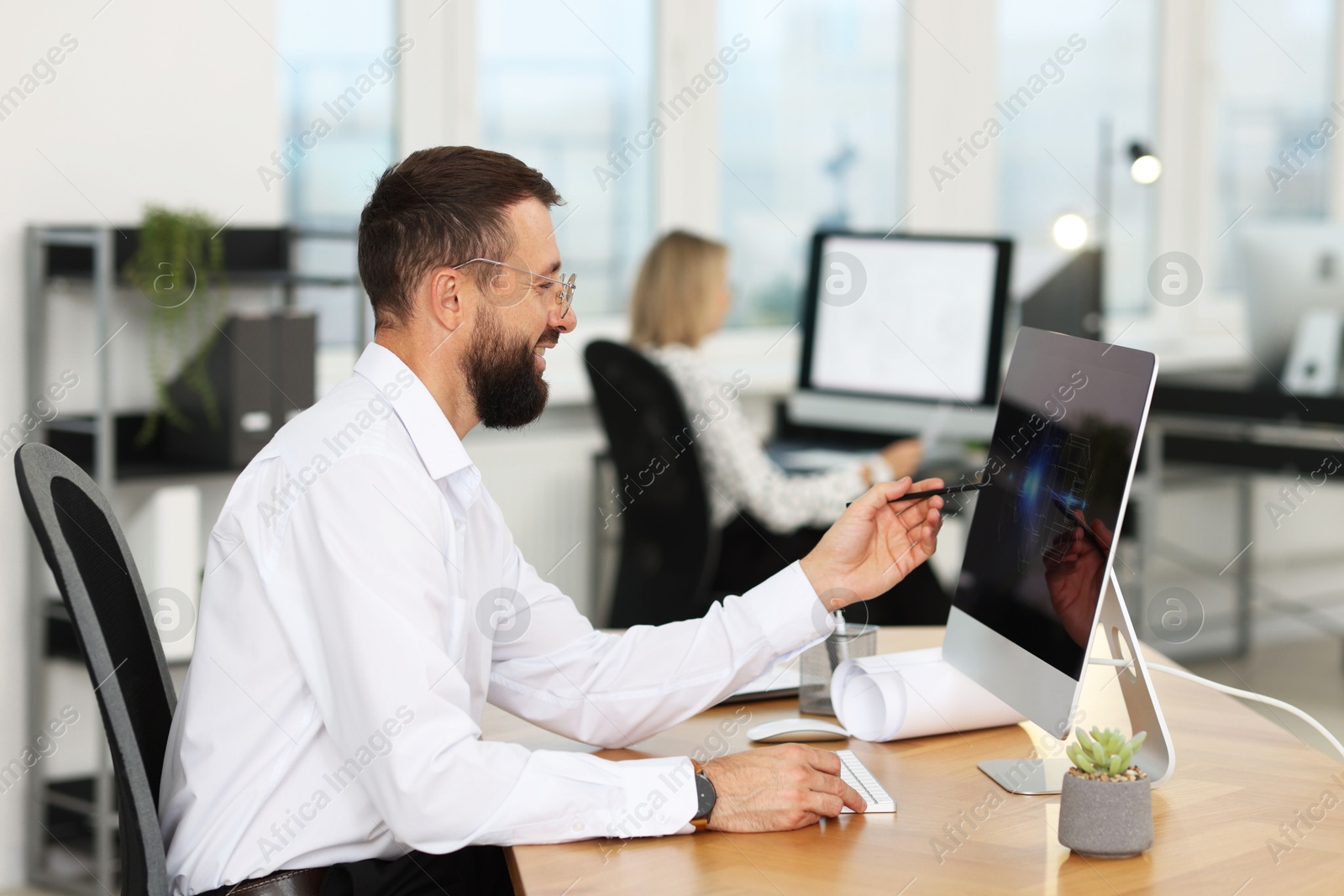 Photo of Technician making digital engineering drawing on computer at desk in office