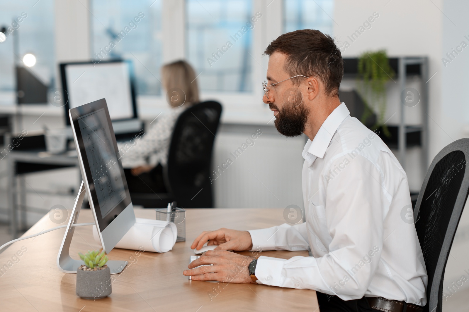 Photo of Technician making digital engineering drawing on computer at desk in office