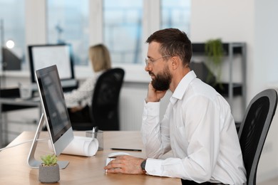 Photo of Technician making digital engineering drawing on computer at desk in office