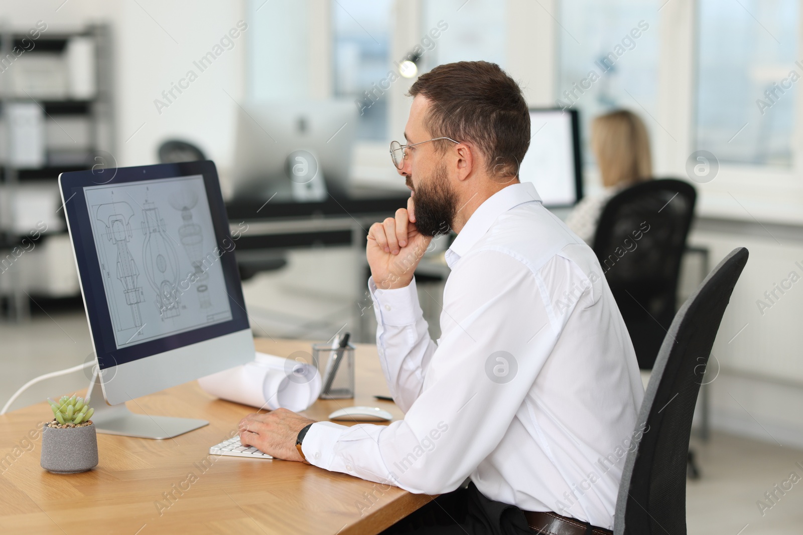 Photo of Technician making digital engineering drawing on computer at desk in office