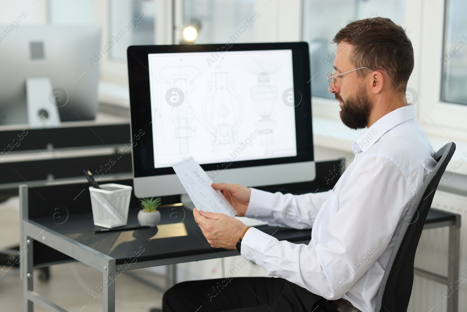 Photo of Technician making digital engineering drawing on computer at desk in office