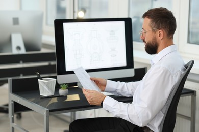 Photo of Technician making digital engineering drawing on computer at desk in office