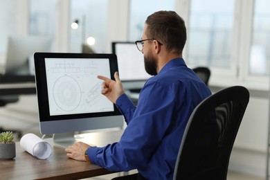 Photo of Technician making digital engineering drawing on computer at desk in office, back view