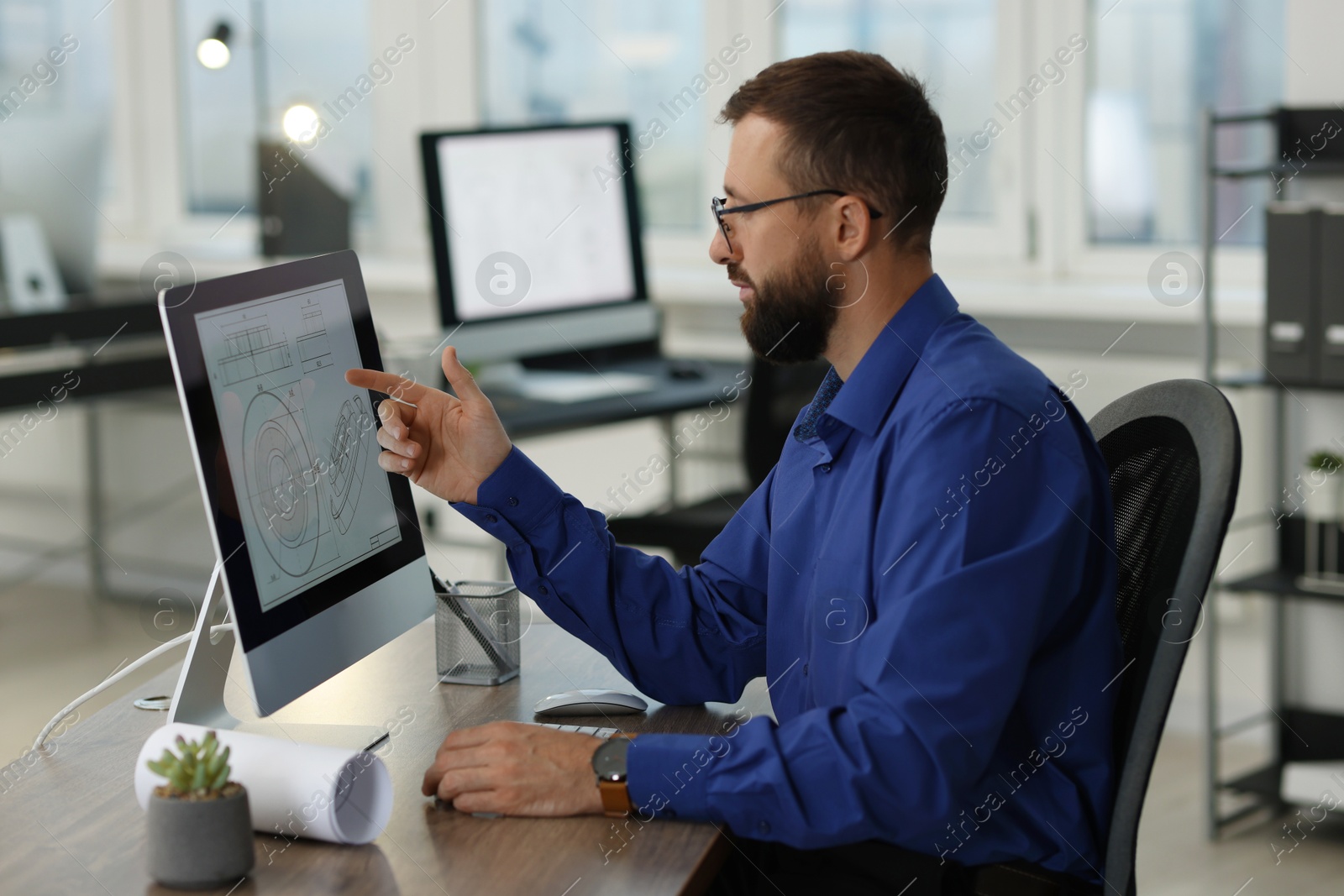 Photo of Technician making digital engineering drawing on computer at desk in office