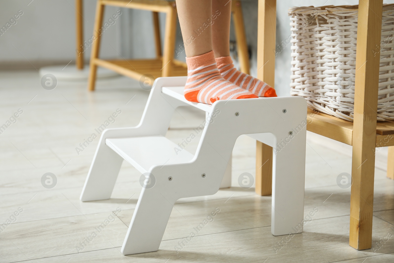 Photo of Little girl standing on step stool indoors, closeup