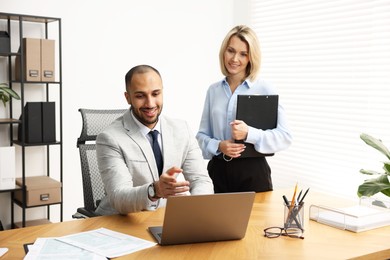 Photo of Coworkers with laptop working together in office