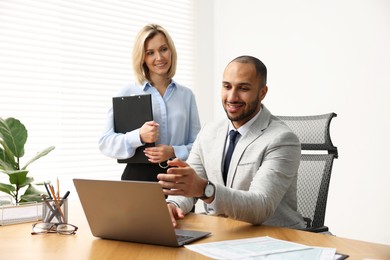 Photo of Coworkers with laptop working together in office