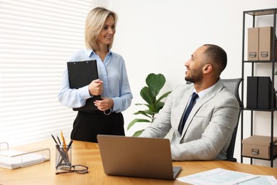 Photo of Coworkers with laptop working together in office