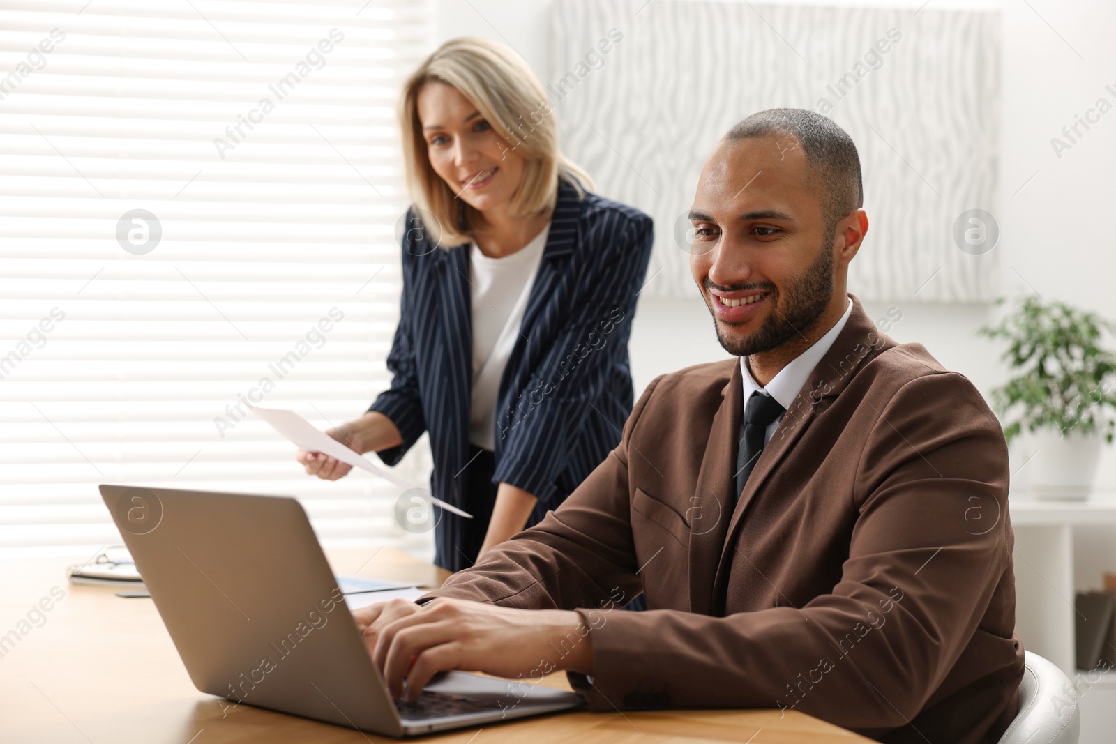 Photo of Coworkers with laptop working together in office