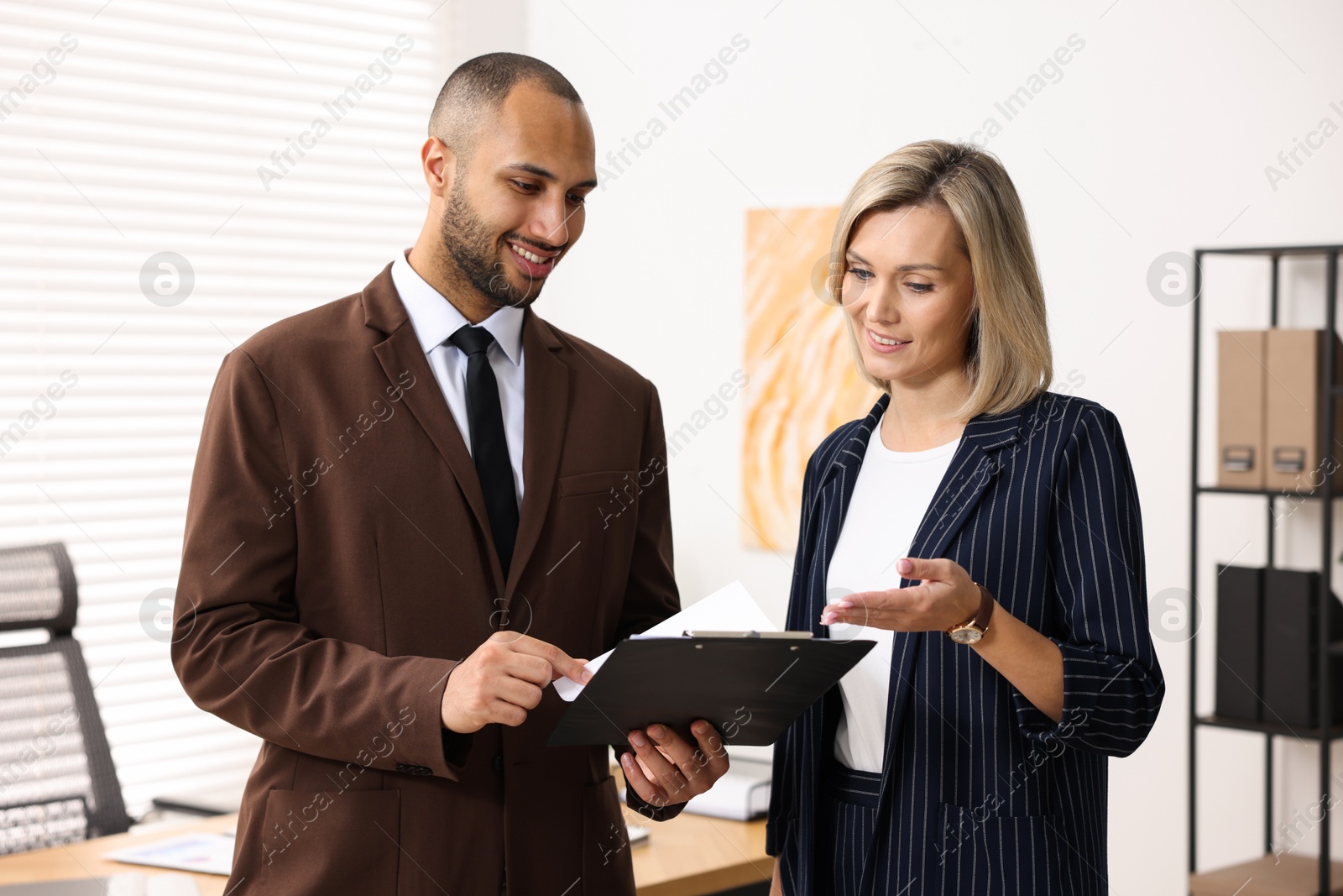 Photo of Coworkers with clipboard working together in office