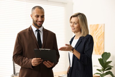 Photo of Coworkers with clipboard working together in office