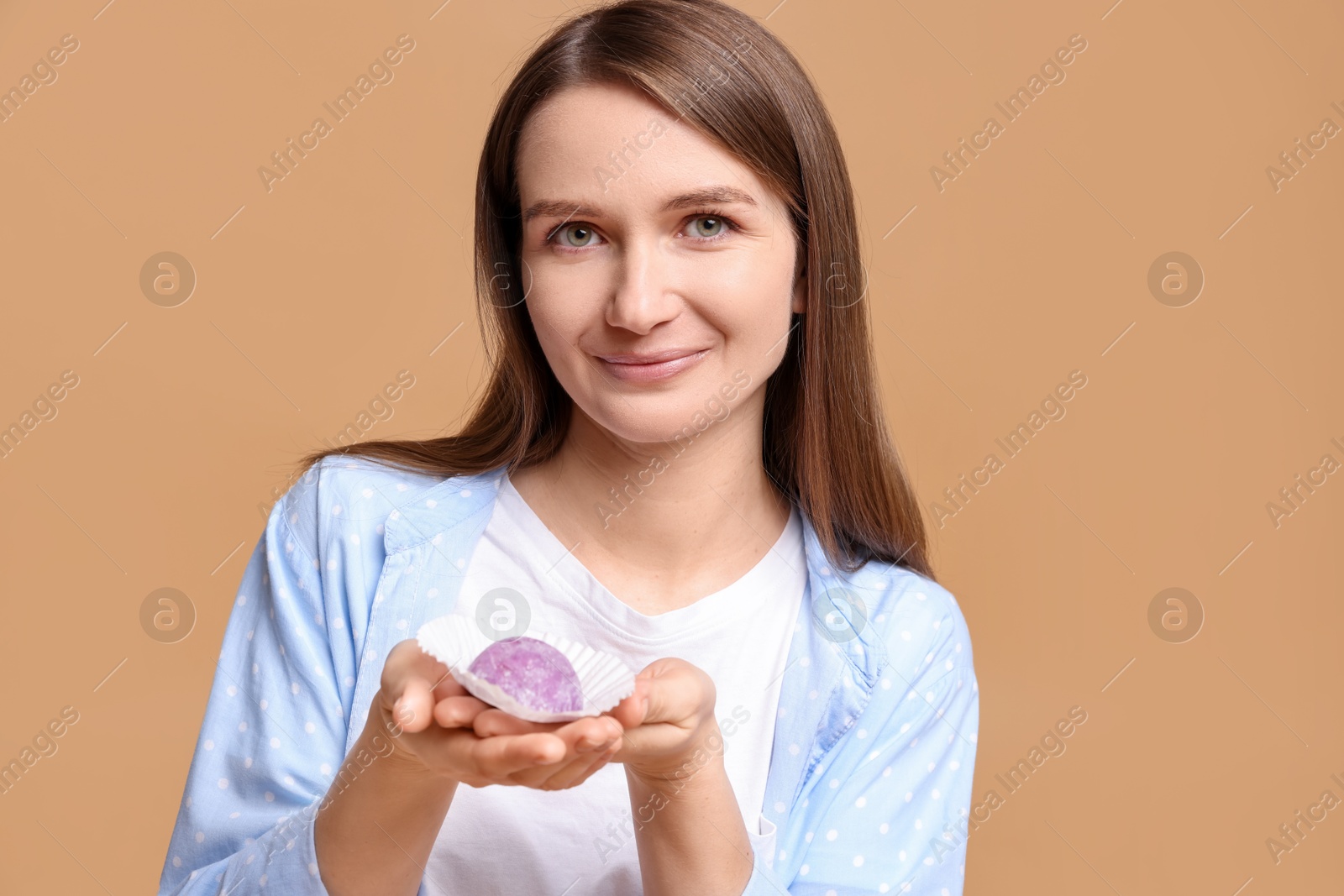 Photo of Woman with tasty mochi on light brown background