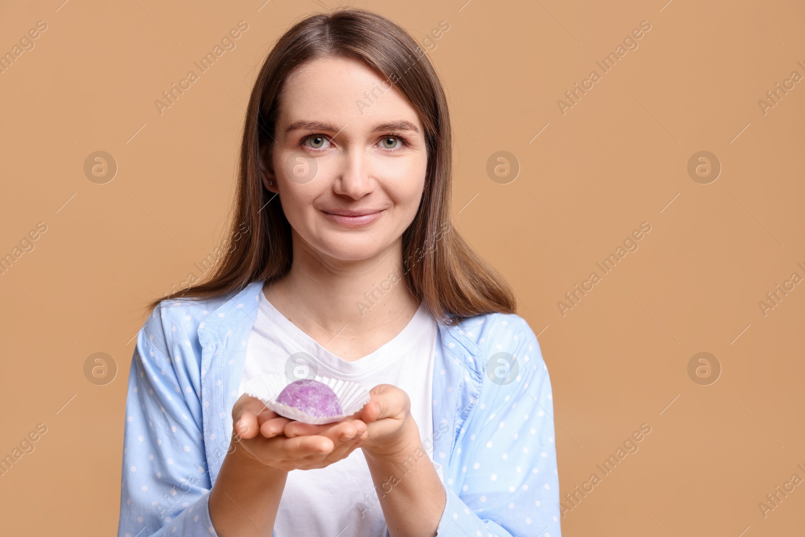 Photo of Woman with tasty mochi on light brown background