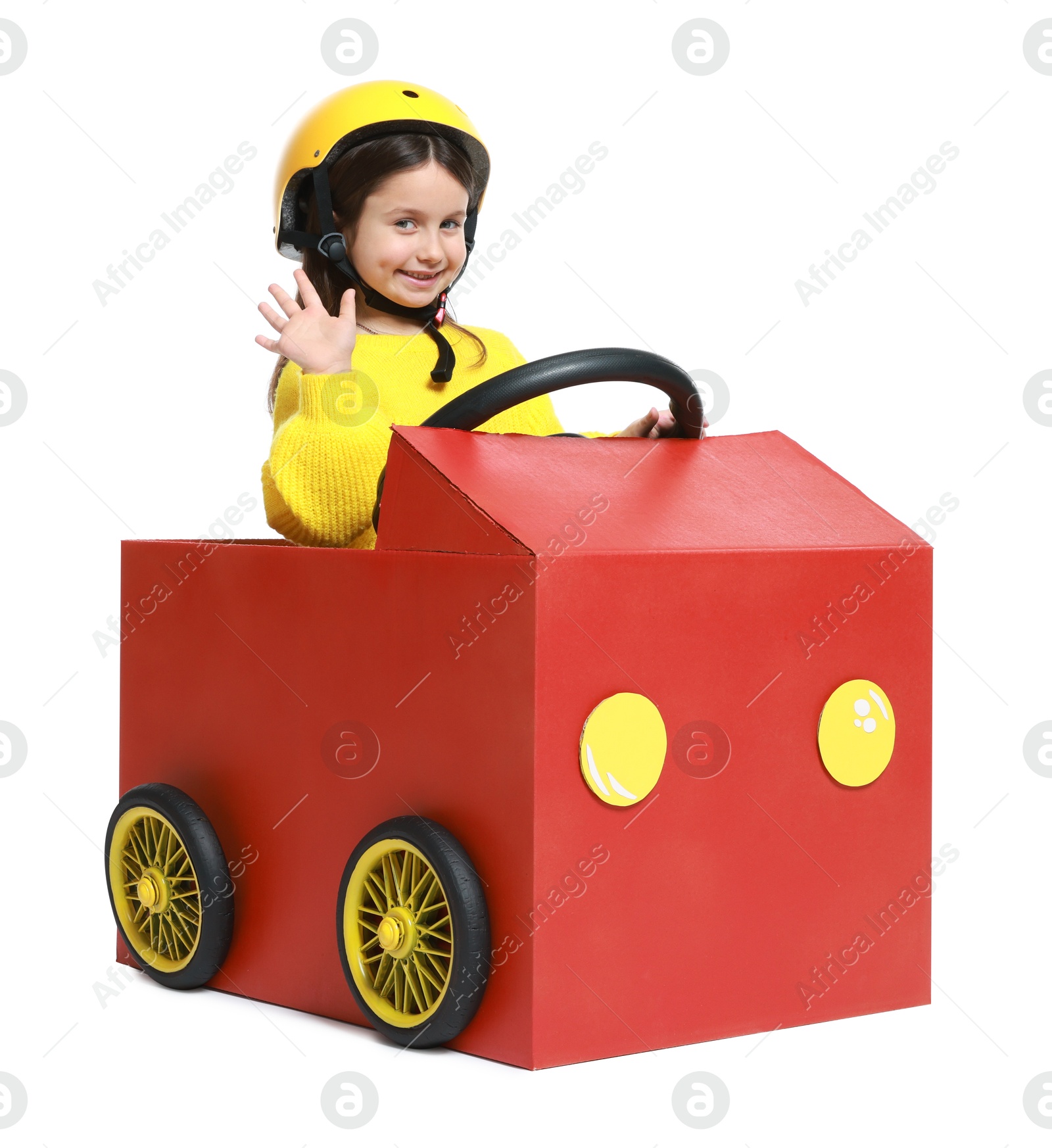 Photo of Little girl waving while driving car made with cardboard on white background