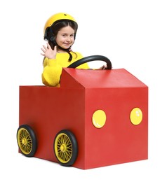 Photo of Little girl waving while driving car made with cardboard on white background